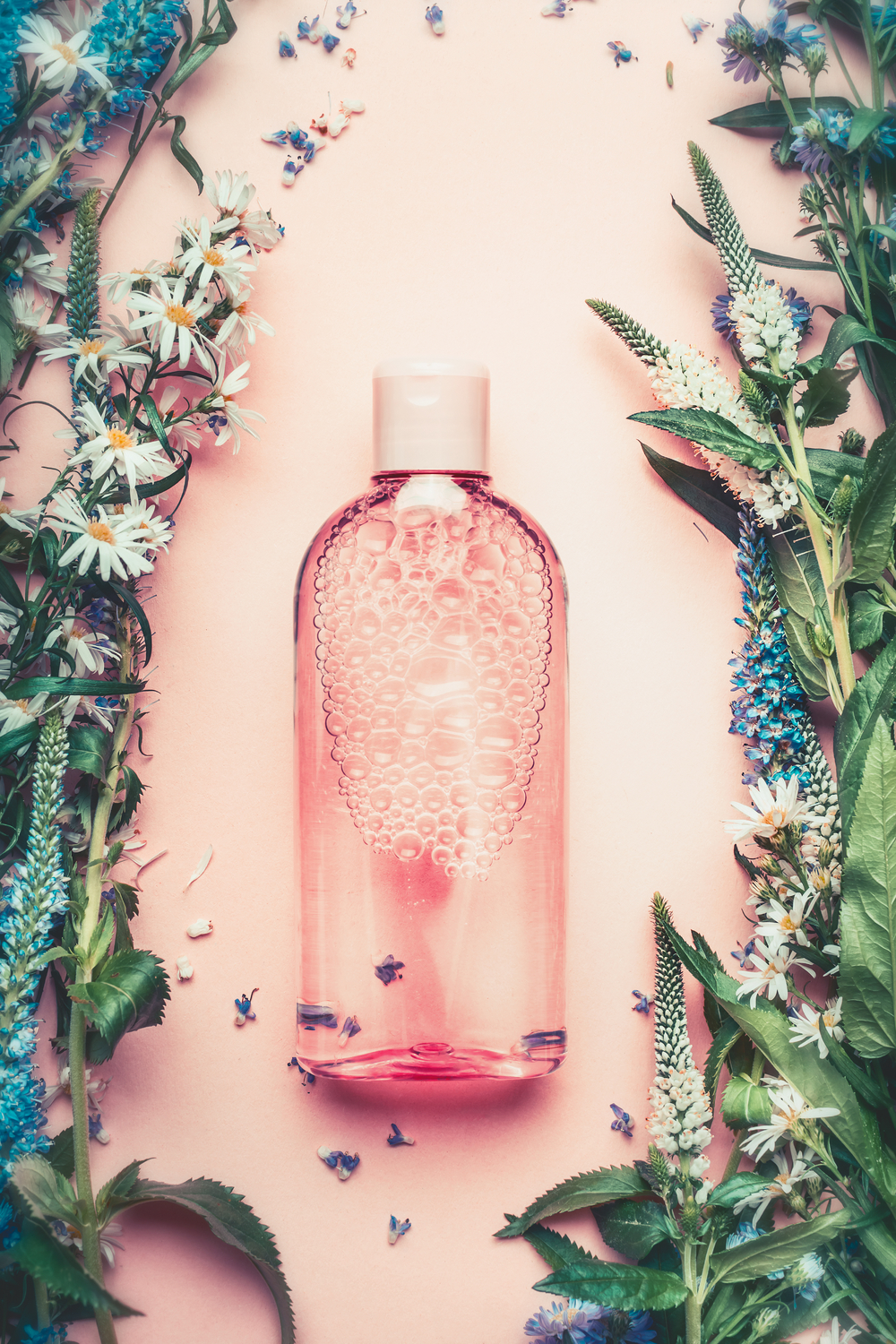 在桃红色苍白背景的自然化妆产品瓶与植物和花顶视图拷贝空间花卉化妆品植物香水的概念